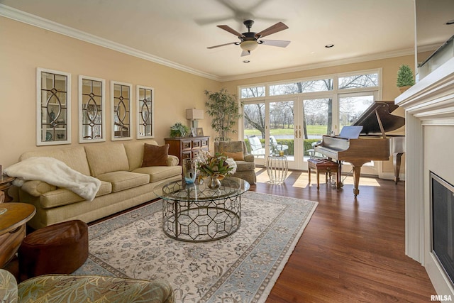living room with a ceiling fan, dark wood-style floors, a fireplace, and ornamental molding