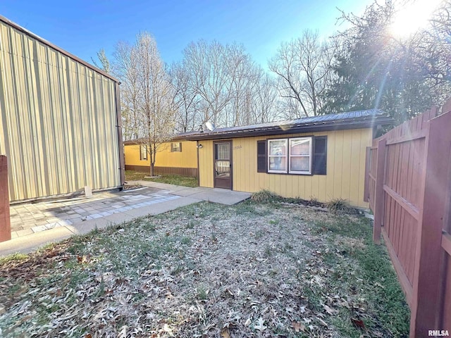 rear view of house with a patio area, fence, and metal roof