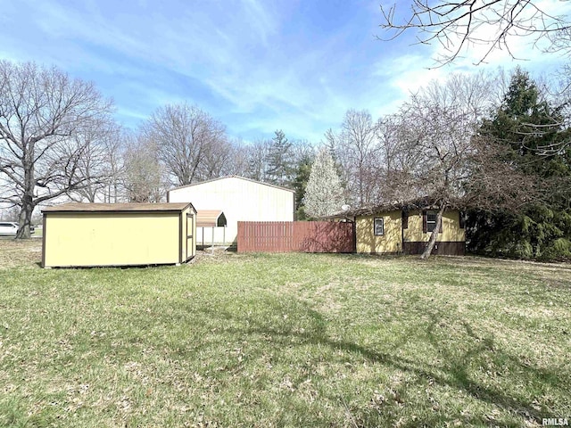 view of yard with a storage unit, an outbuilding, and fence