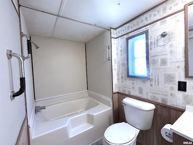 bathroom featuring a bathing tub, toilet, wallpapered walls, and vanity