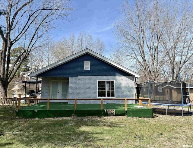 710 S Maple St, Cambria, IL 62915 - rear view of house with fence, a yard, french doors, a trampoline, and brick siding