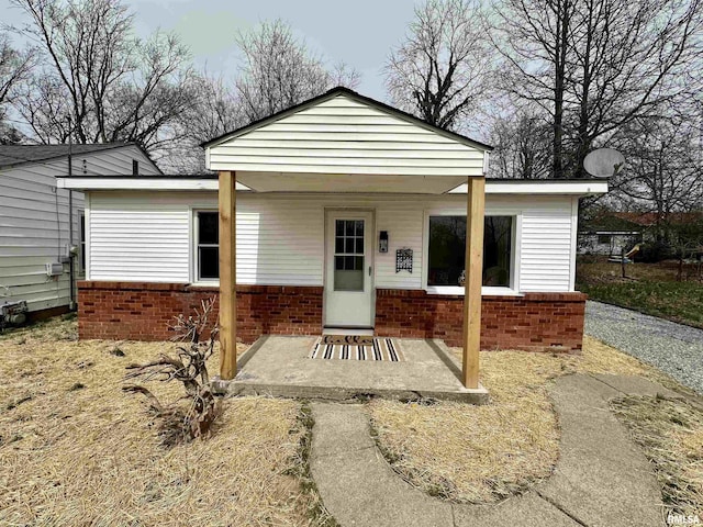 rear view of property with brick siding and covered porch
