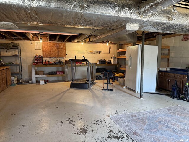 6180 Reevesville Rd, Grantsburg, IL 62943 - basement featuring white refrigerator with ice dispenser, concrete block wall, and a workshop area