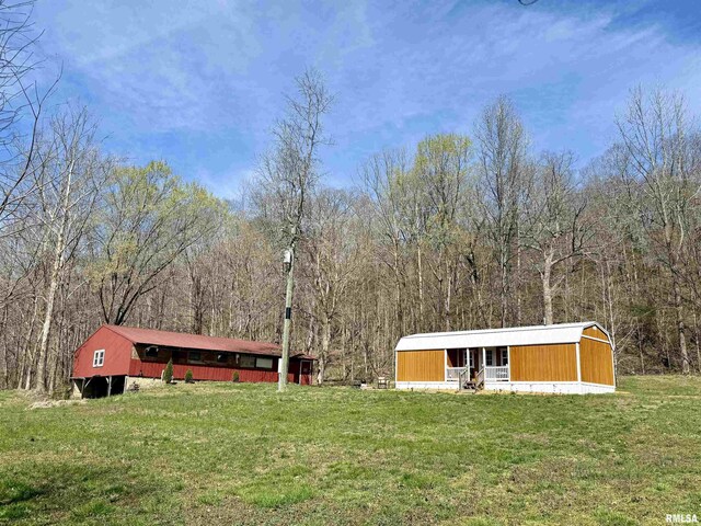 6180 Reevesville Rd, Grantsburg, IL 62943 - view of grassy yard featuring an outbuilding, a wooded view, and an outdoor structure