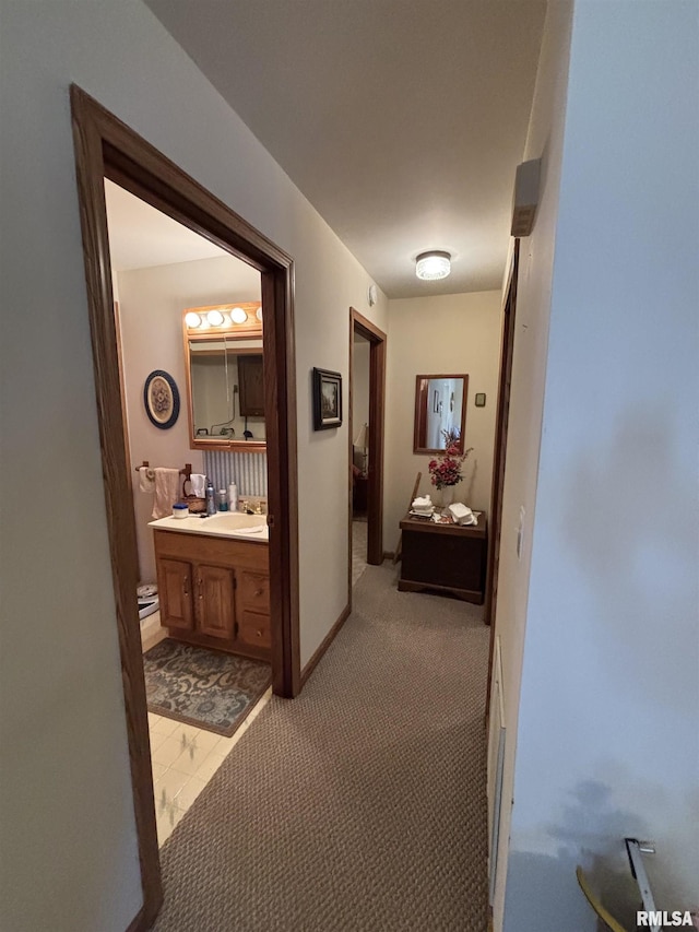 hall featuring baseboards and light carpet