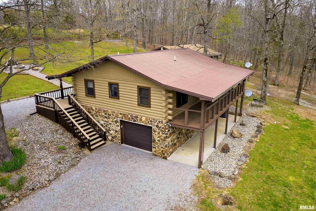 320 Nelson Ln, Grantsburg, IL 62943 - view of front of property with stone siding, gravel driveway, log exterior, an attached garage, and stairs
