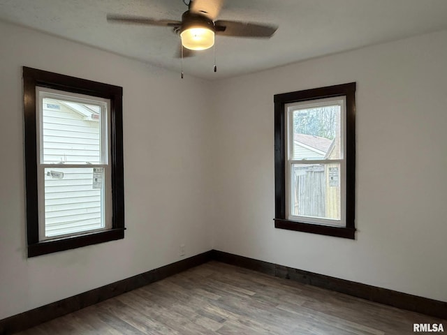 spare room with a ceiling fan, baseboards, and wood finished floors