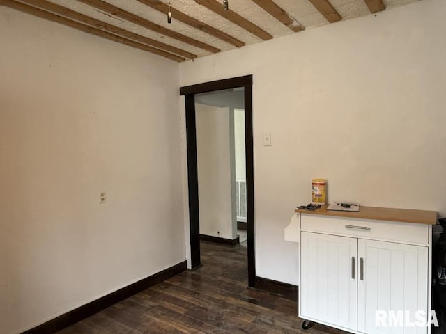empty room with dark wood finished floors, baseboards, beamed ceiling, and visible vents