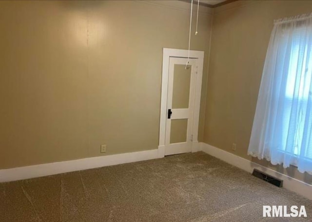spare room featuring carpet floors, crown molding, baseboards, and visible vents