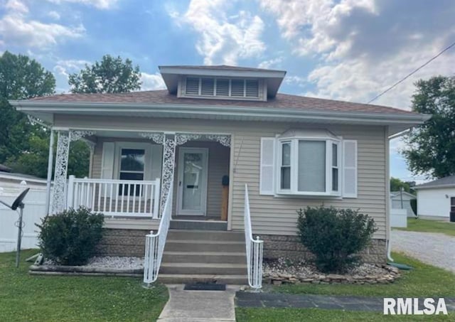 bungalow-style home with covered porch and a front lawn