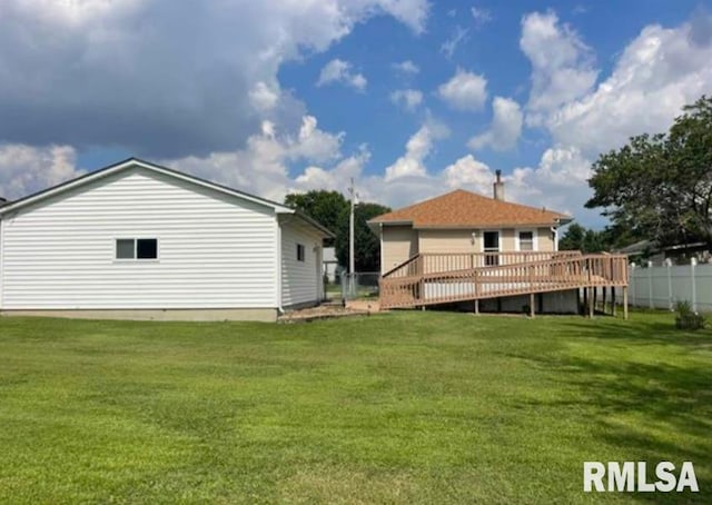 rear view of property with fence, a deck, and a yard