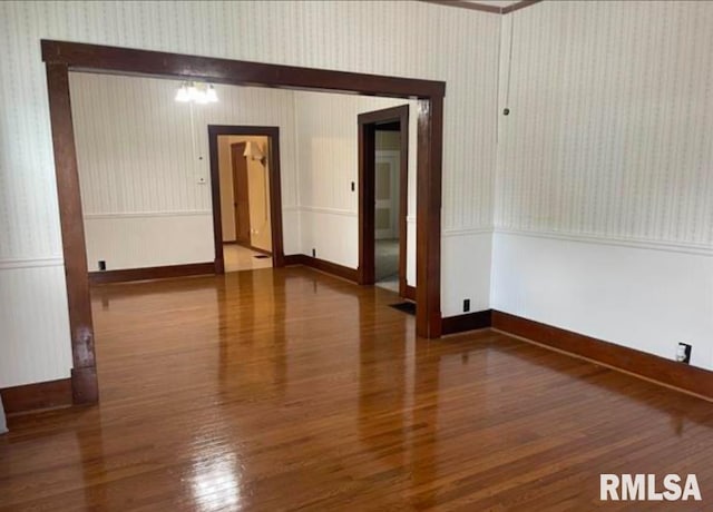 empty room featuring wallpapered walls and wood finished floors