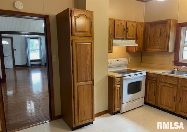 kitchen featuring light countertops, under cabinet range hood, a sink, white electric range, and brown cabinets