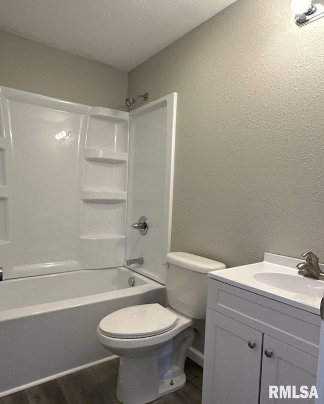 full bathroom with bathtub / shower combination, toilet, vanity, wood finished floors, and a textured wall