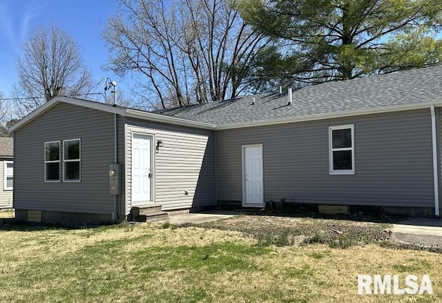 back of property with a lawn, a shingled roof, and entry steps
