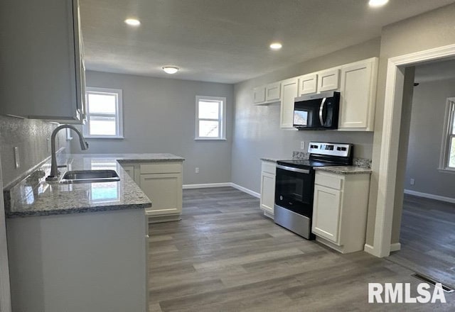 kitchen with baseboards, electric stove, a sink, light stone counters, and wood finished floors