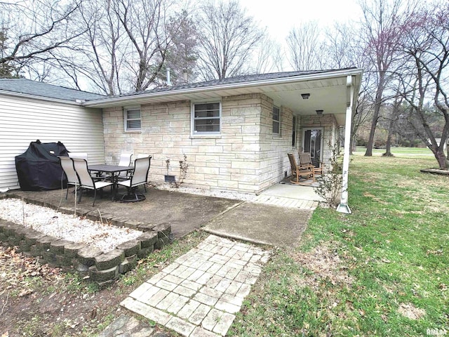 back of house featuring stone siding, a patio, and a yard