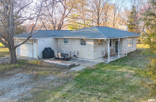 rear view of house featuring stone siding, roof with shingles, an attached garage, a patio, and a lawn