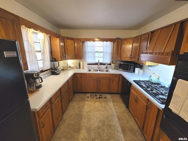 kitchen with black appliances, light countertops, a sink, and brown cabinetry