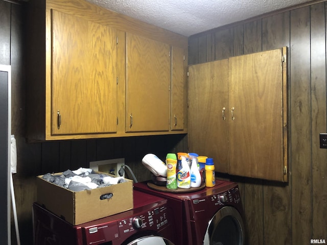 washroom with cabinet space, a textured ceiling, and washer and clothes dryer