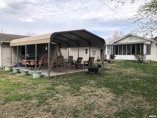 back of property with an outdoor fire pit, a sunroom, and a yard