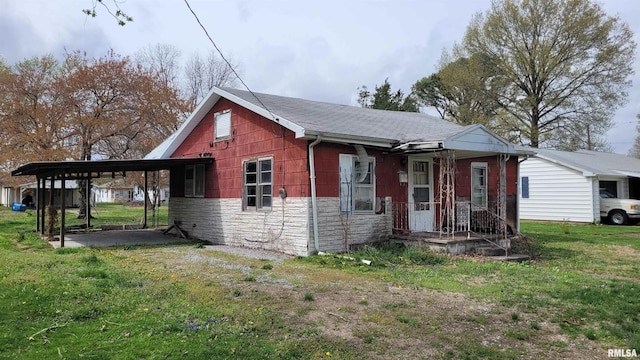 exterior space with stone siding, an attached carport, and a yard