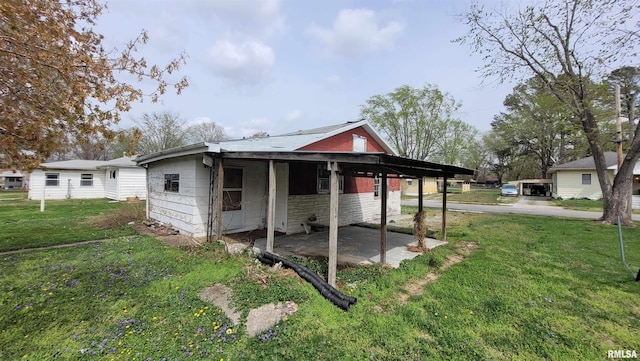 exterior space featuring concrete block siding, a patio, an attached carport, and a lawn