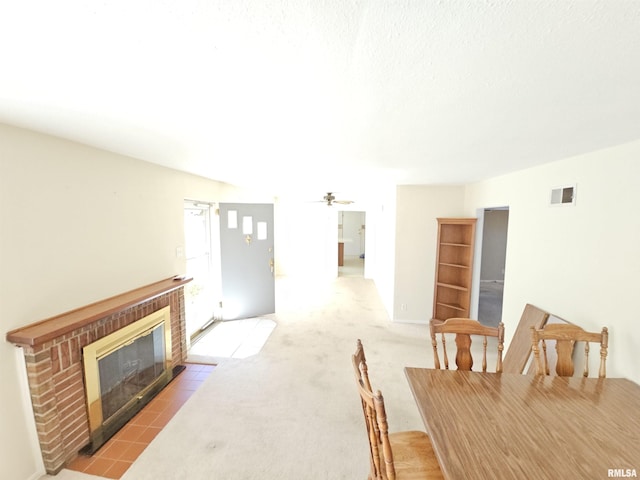 carpeted dining room with a ceiling fan, a fireplace, and visible vents