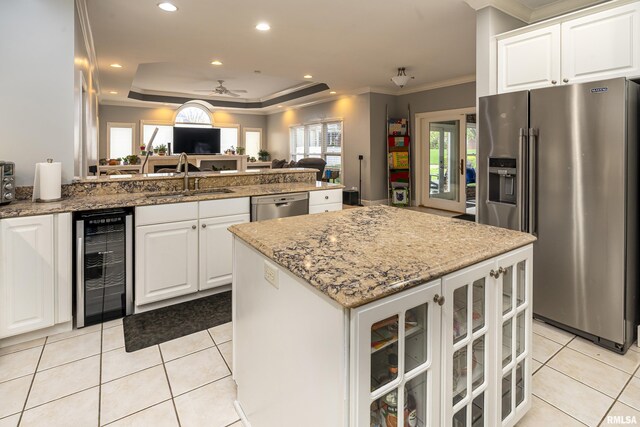 kitchen with a peninsula, a sink, stainless steel appliances, open floor plan, and wine cooler