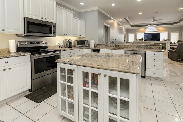 kitchen featuring light tile patterned floors, a sink, open floor plan, a peninsula, and stainless steel appliances