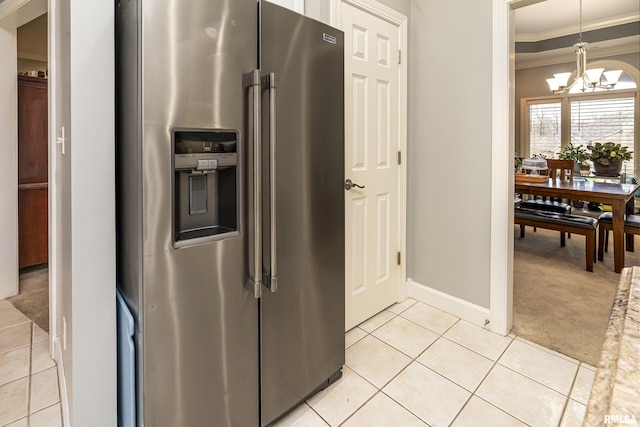 kitchen featuring crown molding, light tile patterned floors, light carpet, stainless steel fridge, and a notable chandelier