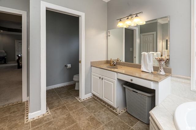 full bath with toilet, vanity, and baseboards