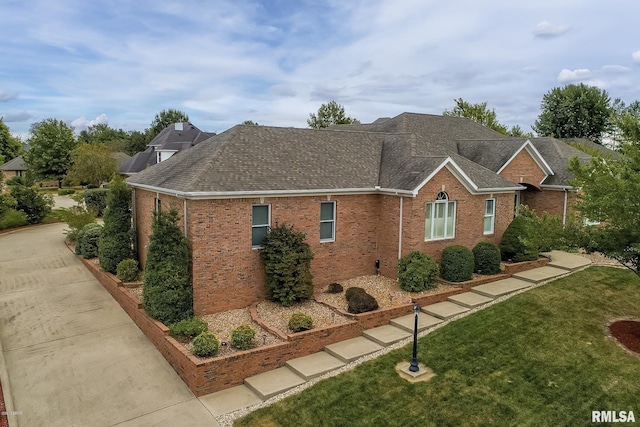 view of home's exterior featuring a yard, brick siding, and a shingled roof