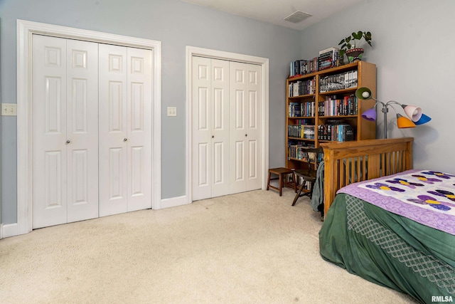 carpeted bedroom with visible vents and multiple closets