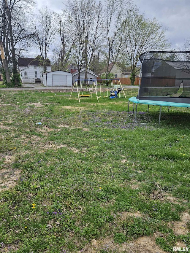 107 W Lincoln St, Harrisburg, IL 62946 - view of yard featuring a detached garage, a trampoline, fence, a playground, and an outbuilding