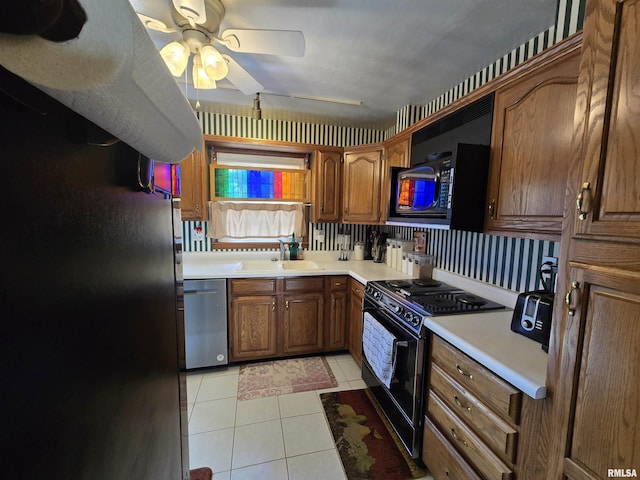 kitchen featuring a sink, light tile patterned flooring, brown cabinetry, black appliances, and a ceiling fan