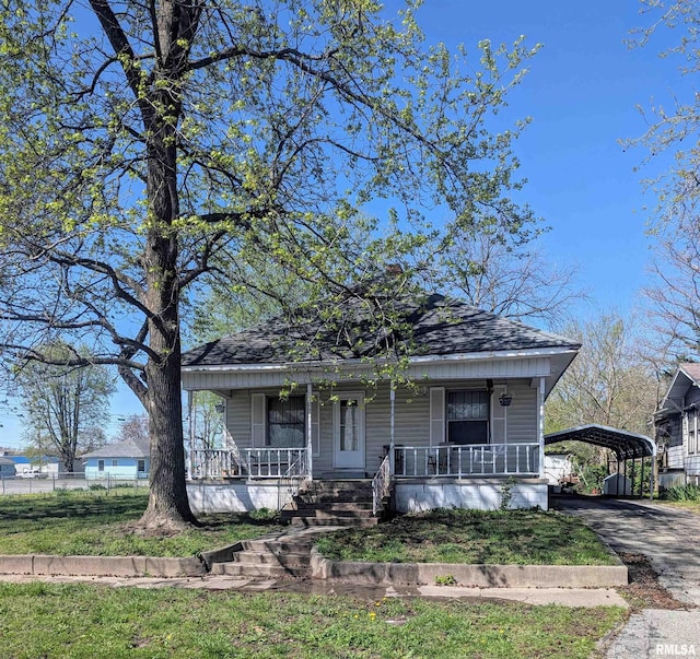 bungalow-style home featuring a detached carport, roof with shingles, covered porch, and aphalt driveway