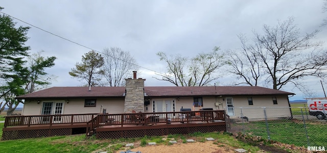 rear view of house with a deck, a chimney, fence, and a lawn