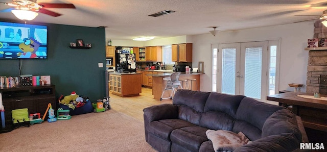 living room with ceiling fan, a textured ceiling, visible vents, light carpet, and french doors
