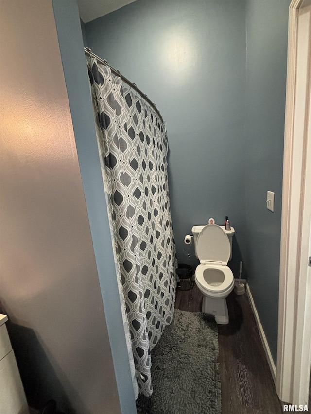 full bath with toilet, curtained shower, wood finished floors, and baseboards
