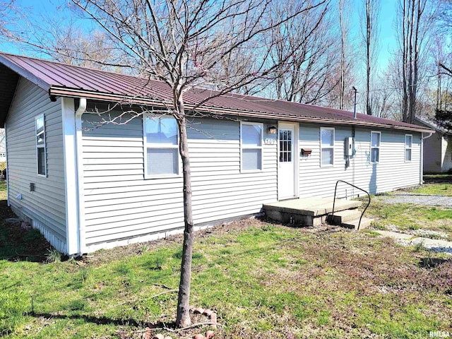 back of house featuring metal roof and a lawn
