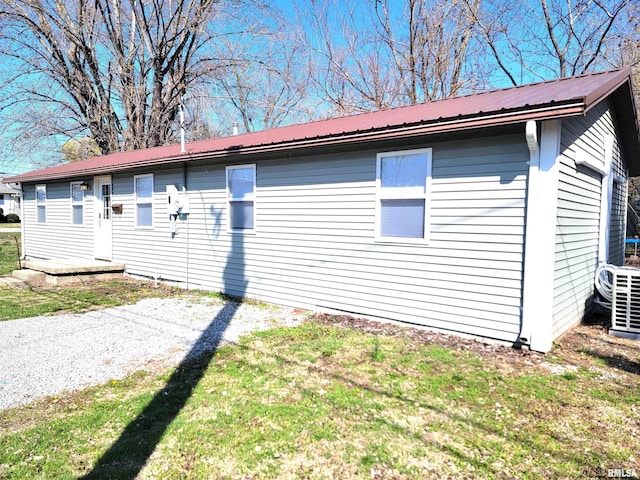 view of side of property featuring metal roof and a lawn