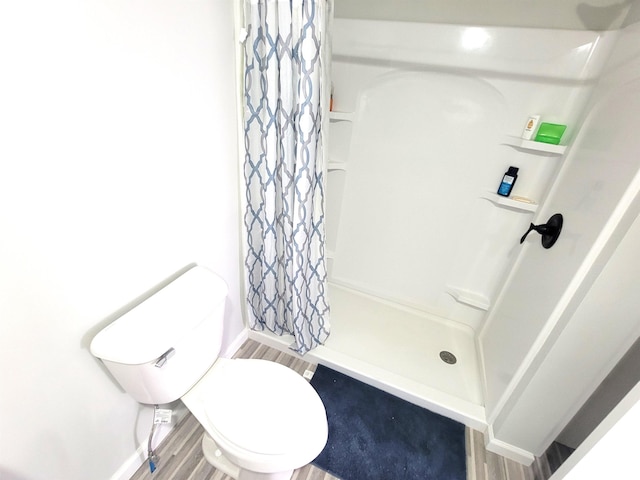 full bathroom featuring a shower stall, wood finished floors, baseboards, and toilet