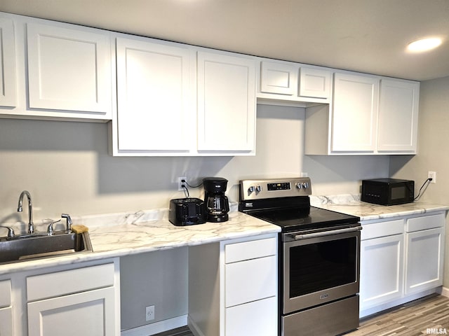 309 E Washington St, Flora, IL 62839 - kitchen featuring stainless steel electric range, black microwave, white cabinets, and wood finished floors