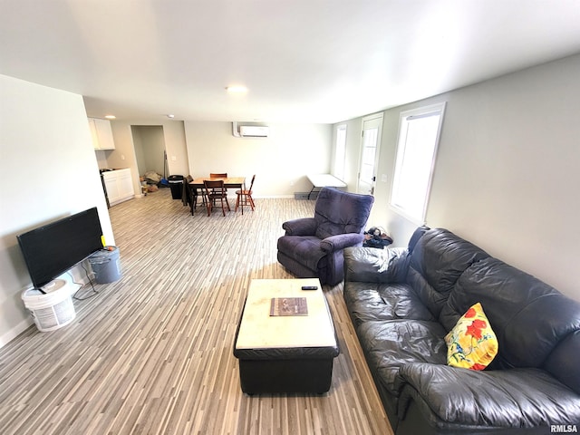 living room featuring an AC wall unit, light wood-style flooring, and baseboards