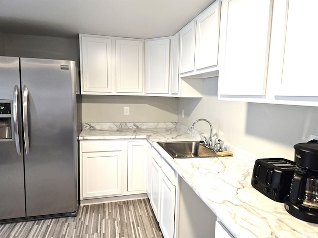 309 E Washington St, Flora, IL 62839 - kitchen with stainless steel refrigerator with ice dispenser, a sink, white cabinetry, light stone countertops, and light wood-type flooring