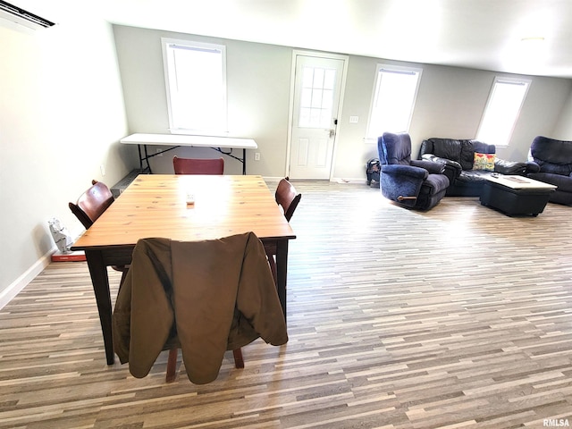dining room with baseboards, wood finished floors, and a wall unit AC