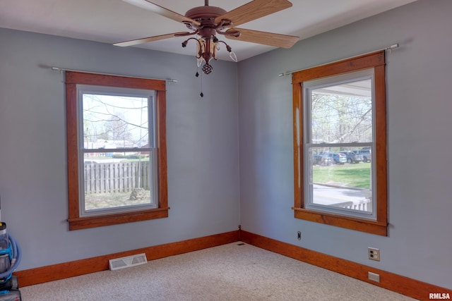 carpeted empty room featuring baseboards, a ceiling fan, and visible vents