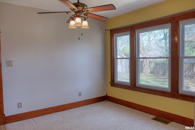 carpeted spare room featuring visible vents, baseboards, and ceiling fan