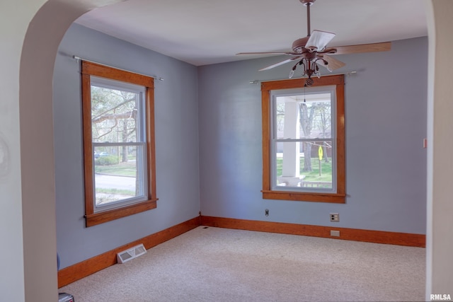 carpeted empty room featuring visible vents, ceiling fan, and baseboards
